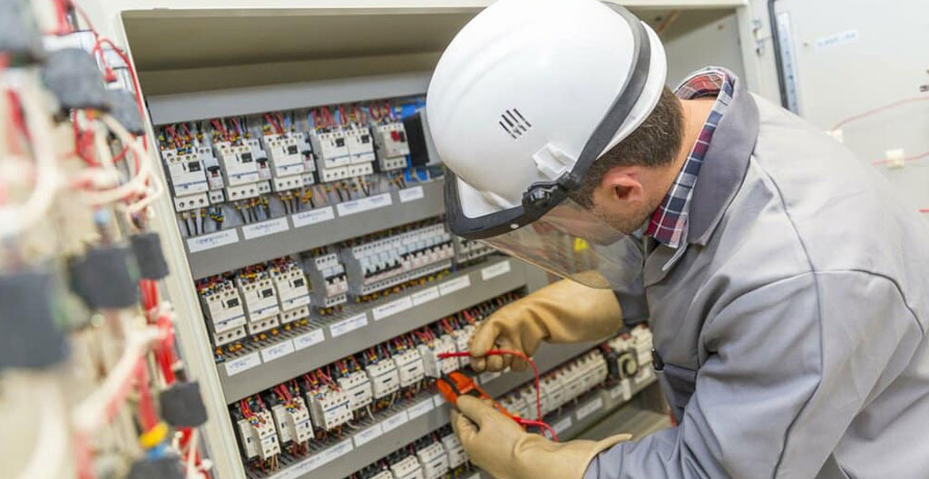 Technicien habilité électrique intervenant sur une armoire électrique industrielle avec équipements de protection individuelle